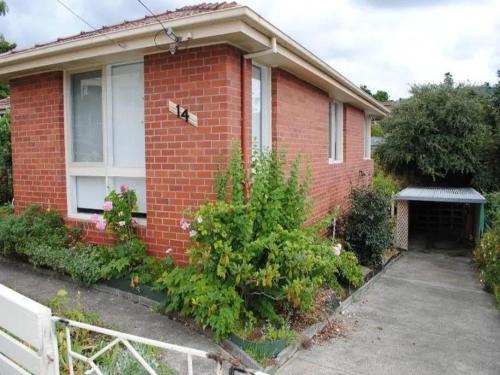 a red brick house with a window and some bushes at Sunny Retreat House in Hobart
