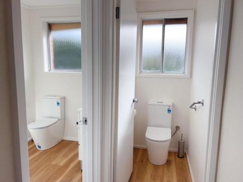 a bathroom with a toilet and two windows at Sunny Retreat House in Hobart