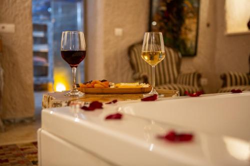 two glasses of wine and a plate of food on a table at Karlık Cave Suite Cappadocia in Uchisar