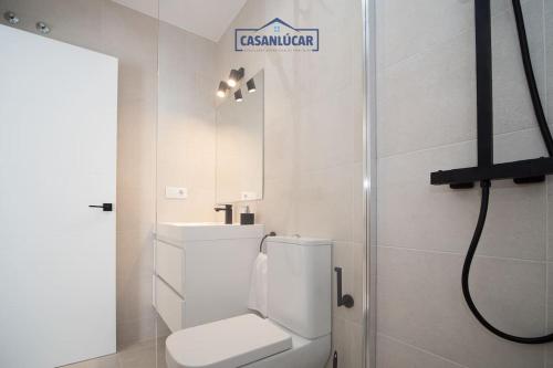 a white bathroom with a toilet and a sink at Sanlucar Centro - Apartamento 1 in Sanlúcar de Barrameda