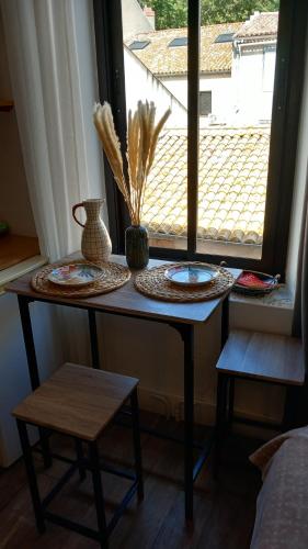 une table dans une pièce avec des assiettes et une fenêtre dans l'établissement Le studio des halles avec climatisation 15m2, à Narbonne