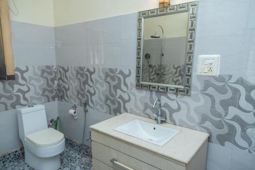 Un baño con inodoro, lavabo y espejo. en The Urban Grandeur 1, en Guwahati