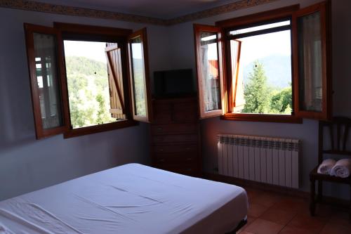 a bedroom with two windows and a white bed at Lanau Casa Barbacoa Bike's Jardín Naturaleza in Morillo de Monclús