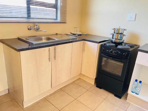a small kitchen with a sink and a stove at Druza’s guest house in Rustenburg