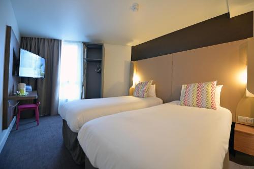 a hotel room with two beds and a tv at CAMPANILE PARIS - Clichy Centre in Clichy