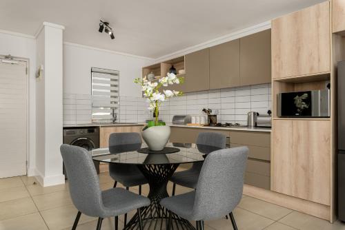 a kitchen with a table with chairs and a vase with flowers at Waters Edge Apartments in Cape Town