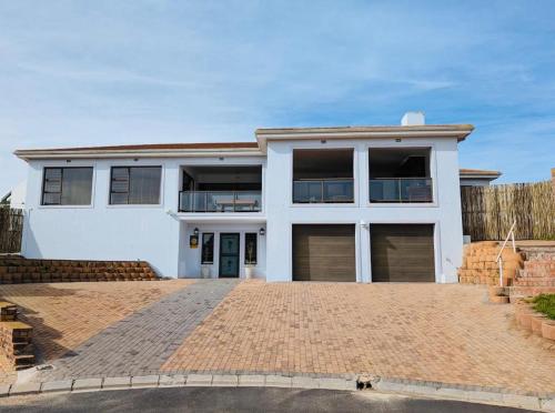 a white house with two garage doors on a brick driveway at Round Robben in Langebaan