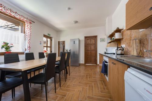 a kitchen with a wooden table and chairs at Fehér Galamb Vendégház in Tolmacs