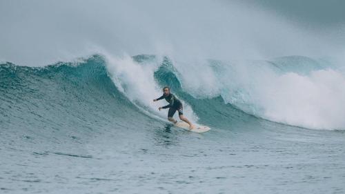 a man riding a wave on a surfboard in the ocean at Marmora Maldives-All-inclusive guesthouse with an excursion everyday in Huraa