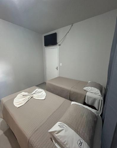 two beds in a hotel room with towels on them at Hotel Monte Carlo in Dourados