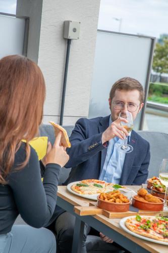 a man and a woman sitting at a table eating pizza at AC Hotel by Marriott Belfast in Belfast