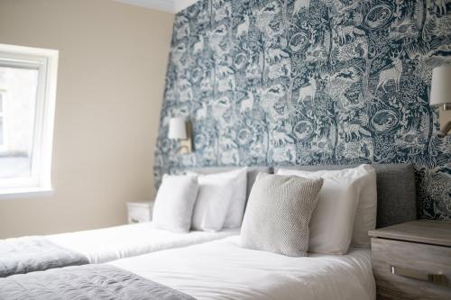 two beds in a bedroom with a blue and white wallpaper at Loch Ness Drumnadrochit Hotel in Drumnadrochit