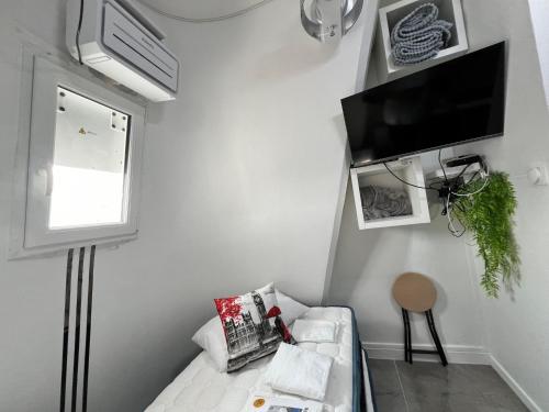 a living room with a couch and a tv on the wall at PARIS BASTILLE BERCY GARE DE LYON CHAMBRE CLIMATISEE 9m2 idéal 1 pers ,max 2 pers in Paris