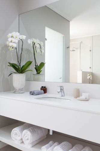 a white bathroom with a sink and a mirror at Pearl Valley Hotel in Franschhoek