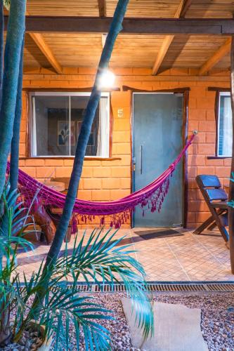 a hammock in front of a house with a door at Pousada Flor de Maio - Vila De São Jorge in Sao Jorge