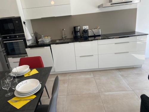 a kitchen with white cabinets and a table with plates on it at SixTer in La Guérinière