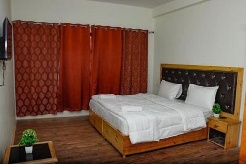 a bedroom with a large bed with red curtains at Semkar Villa Ladakh by LexStays in Leh