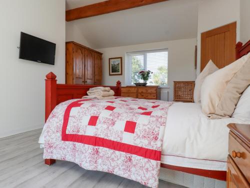 a bedroom with a bed with a red and white quilt at The White House in Pwllheli