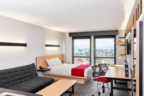 a hotel room with a bed and a couch at City Express by Marriott Mérida in Mérida