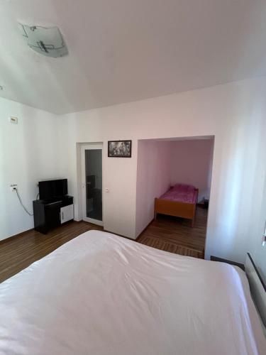a bedroom with a white bed and a room with a television at Casa de vacanță Fabian in Vişeu de Jos