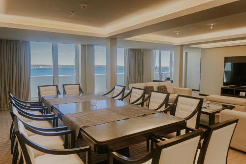 a dining room with tables and chairs and a television at Rayentray Grand Hotel in Puerto Madryn
