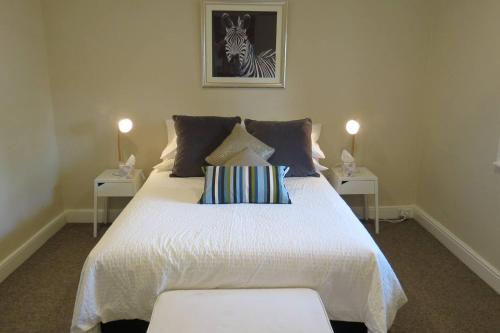 a bedroom with a large white bed with two side tables at Stylish country cottage in central Orange in Orange