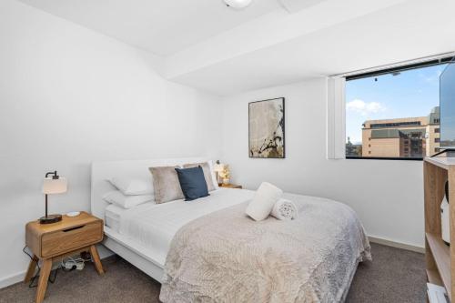a white bedroom with a bed and a window at City Life 2BR Apt with Pool,Gym, Sauna, Carbay in Perth