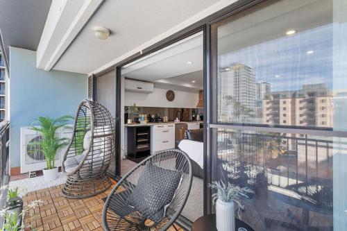 an apartment balcony with two chairs and a kitchen at City Life 2BR Apt with Pool,Gym, Sauna, Carbay in Perth