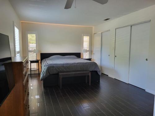 a bedroom with a bed and a dresser and windows at Comfortable home, heated salt-cell pool, 10 min to beach in Sarasota