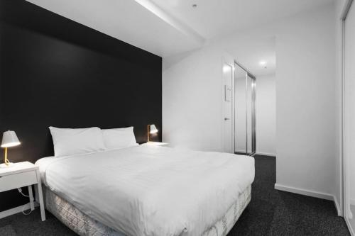 a bedroom with a large white bed and a black wall at Brilliant 2BR Apartment in Belconnen - Hosted by Canstay in Belconnen
