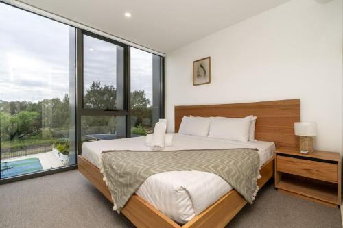 a bedroom with a large bed and a large window at Stylish 2BR Apt 5 mins to Canberra Hospital - Hosted by Canstay in Phillip