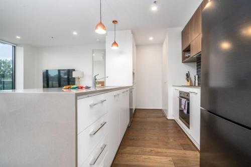 a kitchen with white cabinets and a wooden floor at Stylish 2BR Apt 5 mins to Canberra Hospital - Hosted by Canstay in Phillip