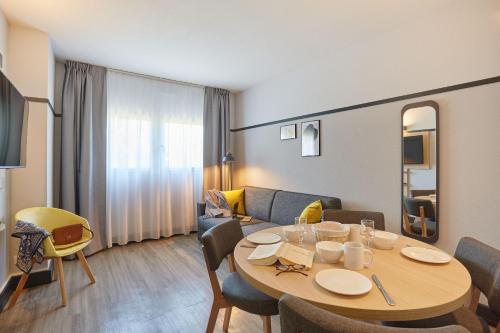 a living room with a table and a couch at Appart Hotel Odalys City Aix en Provence L'Atrium in Aix-en-Provence