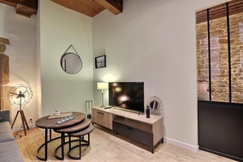 un salon avec une télévision à écran plat et une table dans l'établissement Le Trois Maries - Cozy Apartment - Lyon 5th, à Lyon
