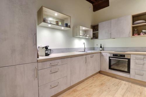 une cuisine avec des armoires blanches et un plancher en bois dans l'établissement Le Trois Maries - Cozy Apartment - Lyon 5th, à Lyon
