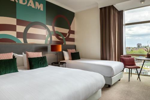 a hotel room with two beds and a window at Apollo Hotel Amsterdam, a Tribute Portfolio Hotel in Amsterdam