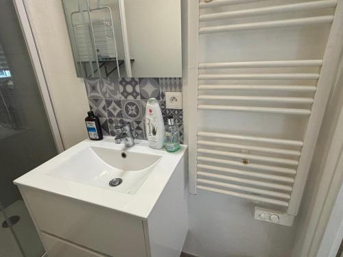 une salle de bain blanche avec un lavabo et un miroir dans l'établissement La Fontaine Wifi Parking Un Séjour à Part, à Hagondange