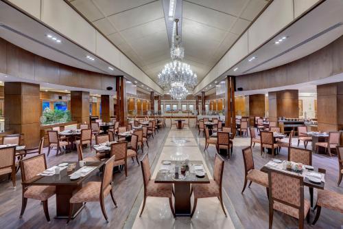 a restaurant with tables and chairs and a chandelier at Islamabad Marriott Hotel in Islamabad