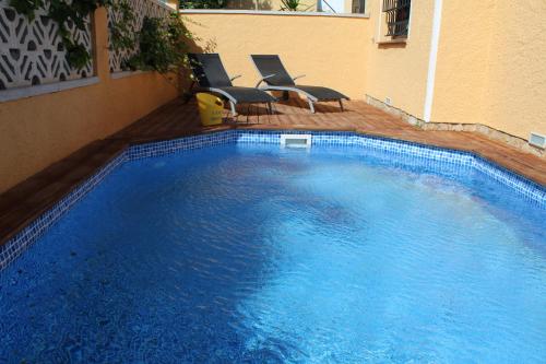 a large blue swimming pool with two chairs next to a building at Casa Montgri in Empuriabrava