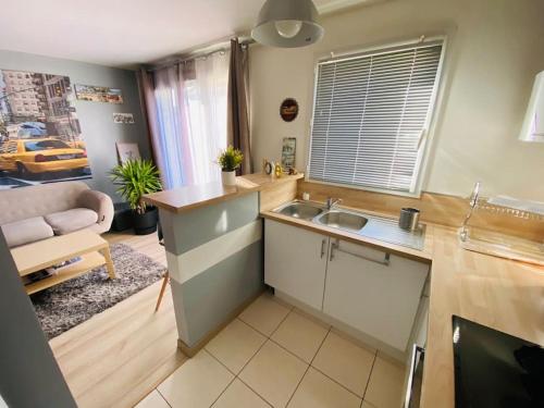 a kitchen with a sink and a couch in a room at Appartement 2 chambres in Mantes-la-Ville
