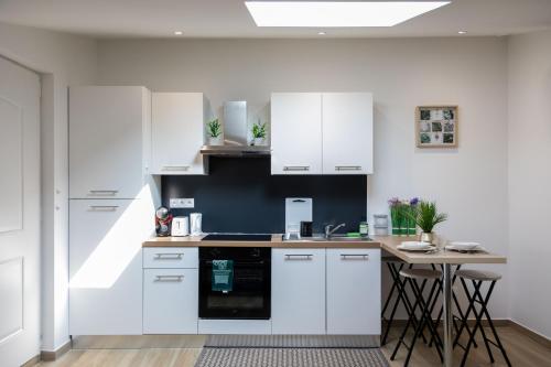 une cuisine avec des armoires blanches et une table dans l'établissement Logement Insolite Ancienne Soue à Cochons Rénovée, à Casteljaloux