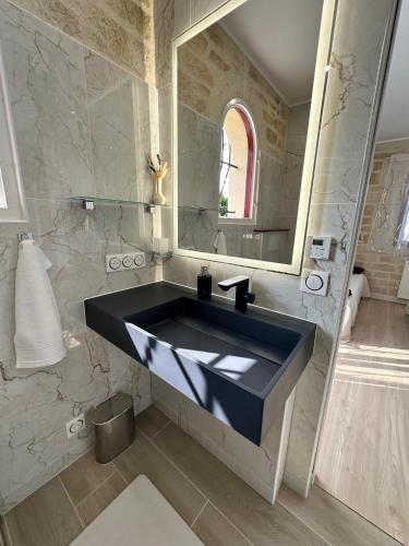 a bathroom with a black sink and a mirror at Le mas des anges in Soussans