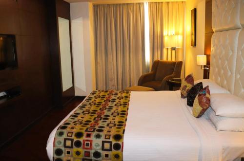 Una habitación de hotel con una cama grande y una silla. en Sangam Hotel, en Chirāwa