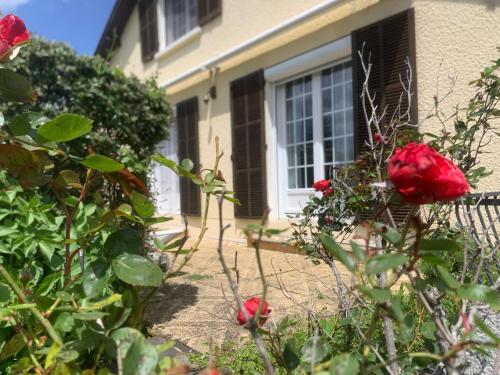 une maison avec des roses rouges devant une fenêtre dans l'établissement Maison familiale, à Paulhac