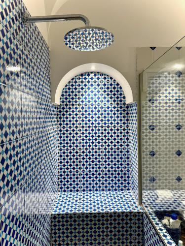 a blue tiled bathroom with a shower with a mirror at L'Ancora Amalfi Dreams in Minori