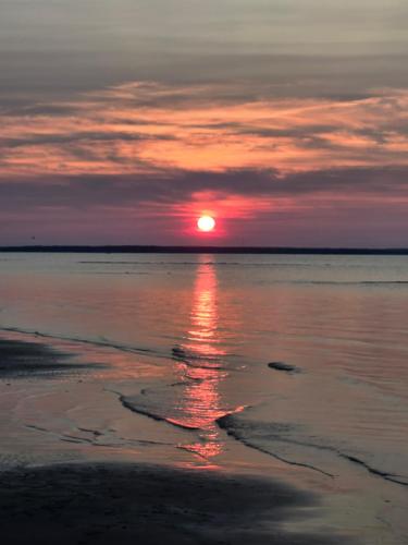 a sunset on the beach with the sun setting at Cozy cottage with private beach access in Grand Barachois