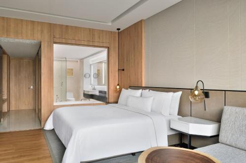 a bedroom with a large white bed and a couch at The Westin Mumbai Powai Lake in Mumbai