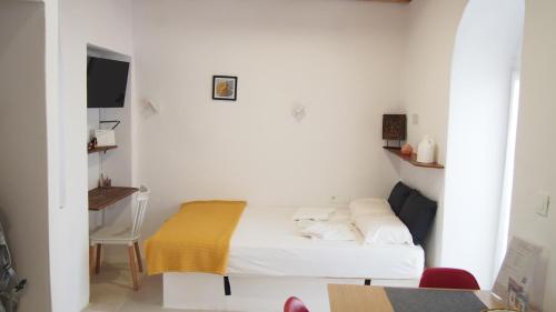 Kleines weißes Zimmer mit einem Bett und einem Schreibtisch. in der Unterkunft Little House in Káto Petálion