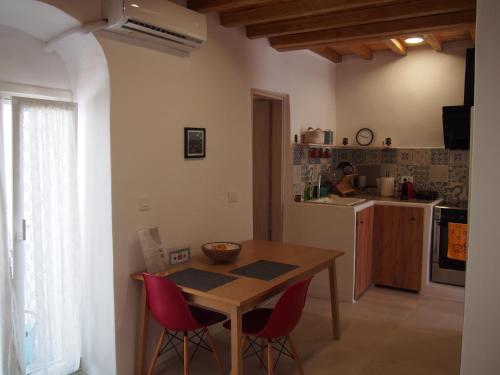 eine Küche mit einem Holztisch und roten Stühlen in der Unterkunft Little House in Káto Petálion