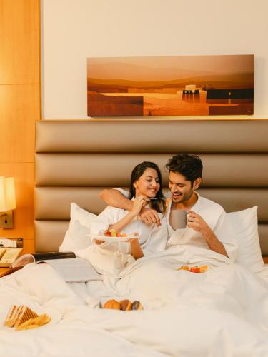 a man and a woman sitting in bed at Hyatt Regency Pune Hotel & Residences in Pune